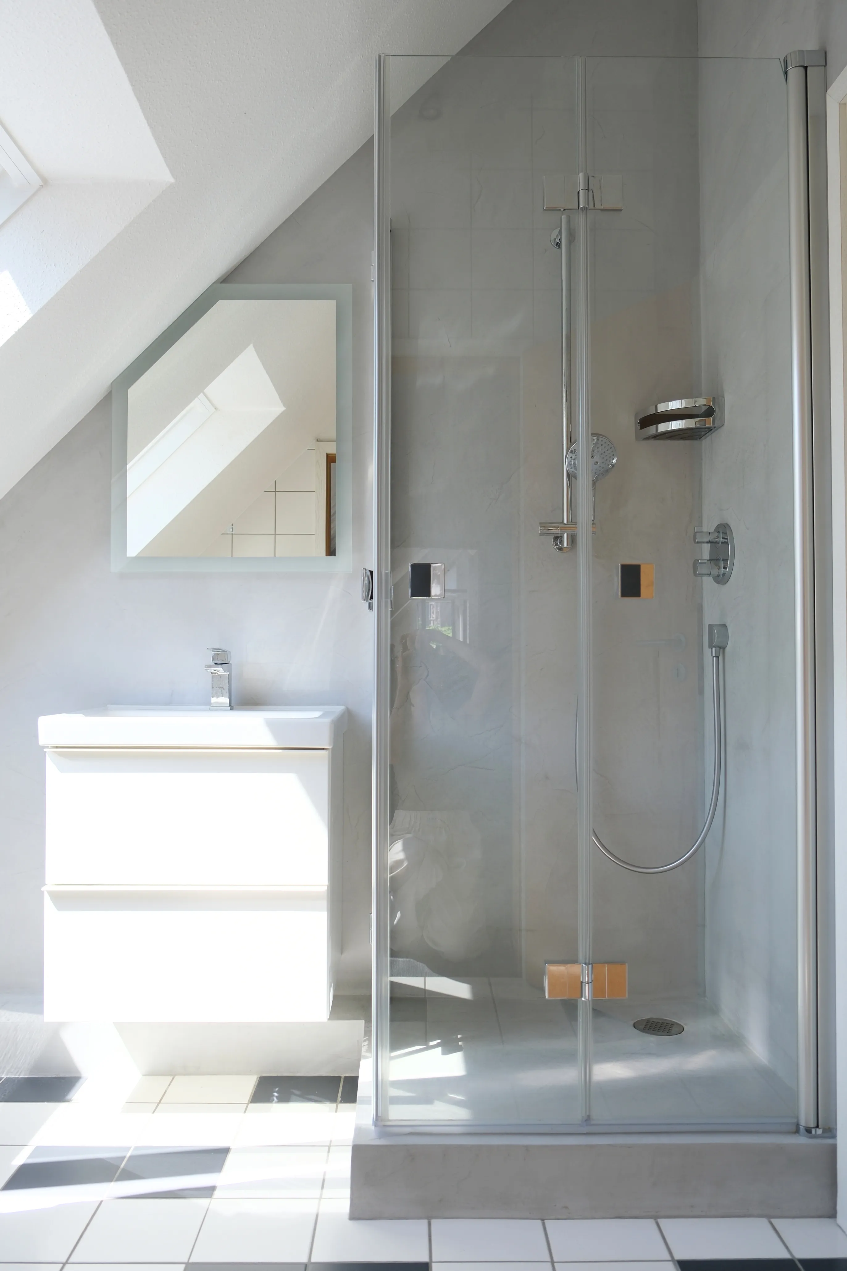 Waschtisch mit Spiegel und Dusche, fugenlose graue Wandfläche