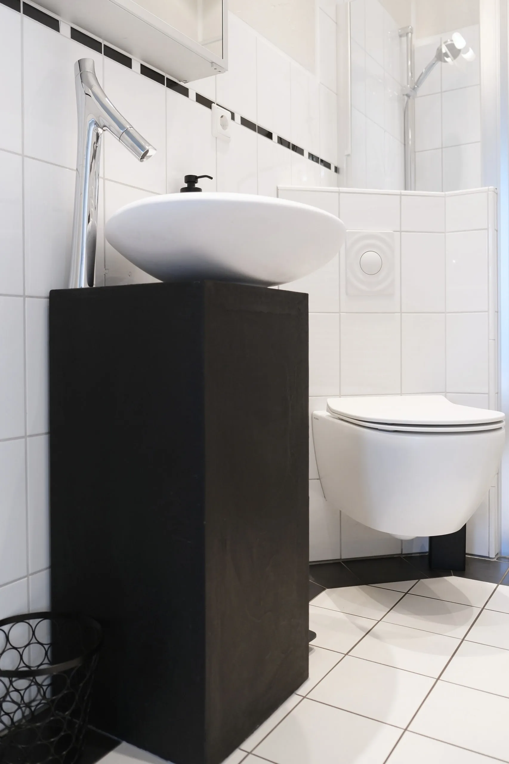 Aufsatzwaschtisch auf dunklem Sockel neben dem wandhängenden WC