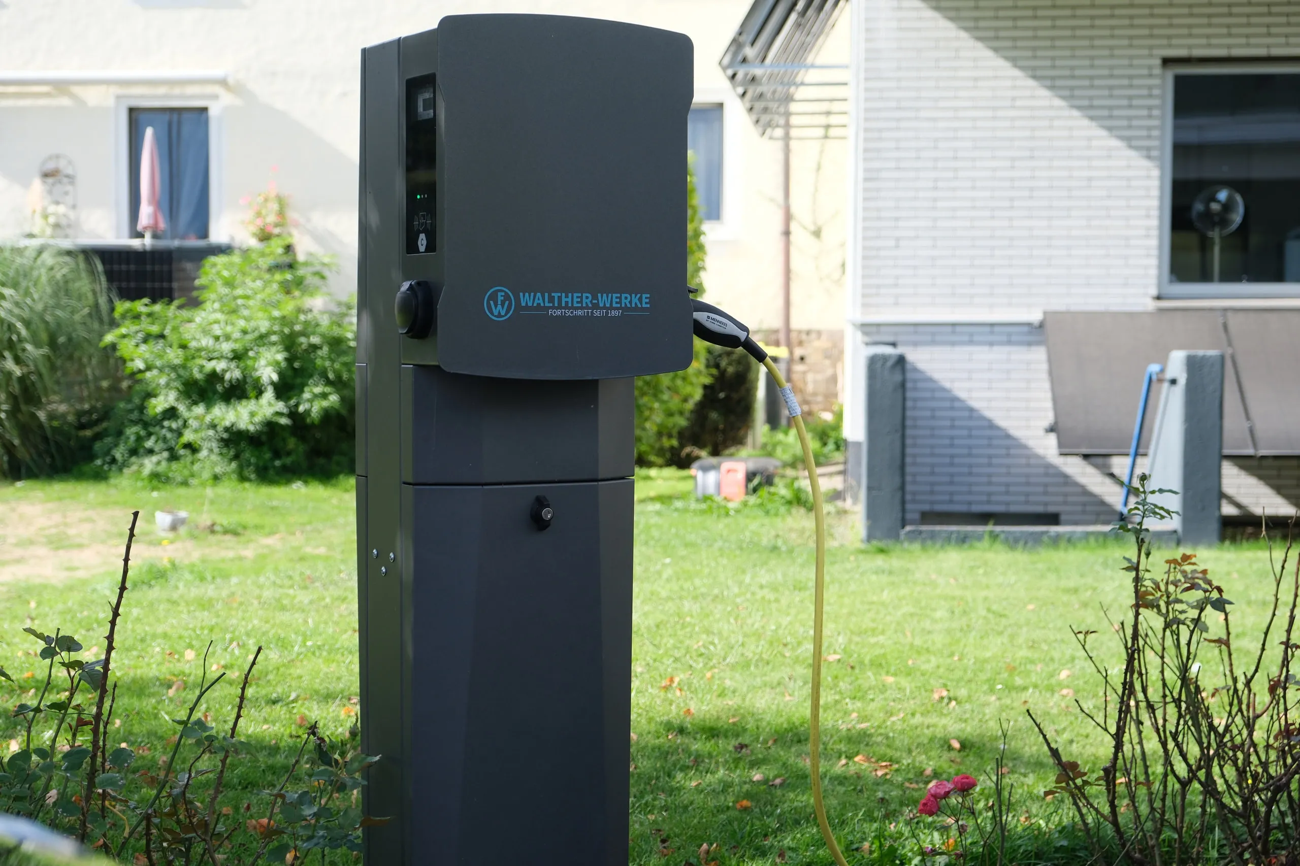 Freistehende Wallbox-Ladesäule im Garten eines Einfamilienhauses