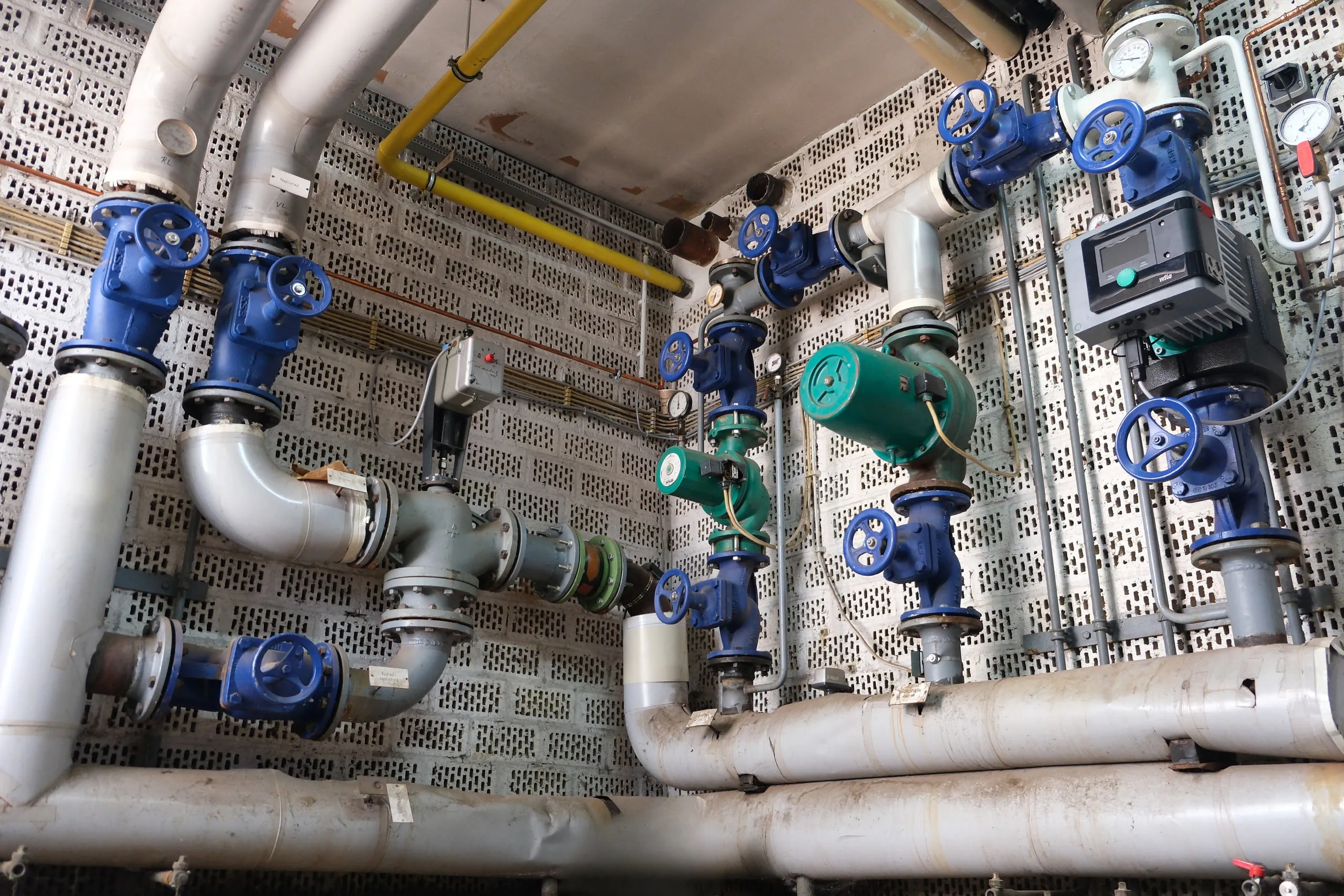 Armaturen, Pumpen und Gasleitung an der Wand der Heizzentrale