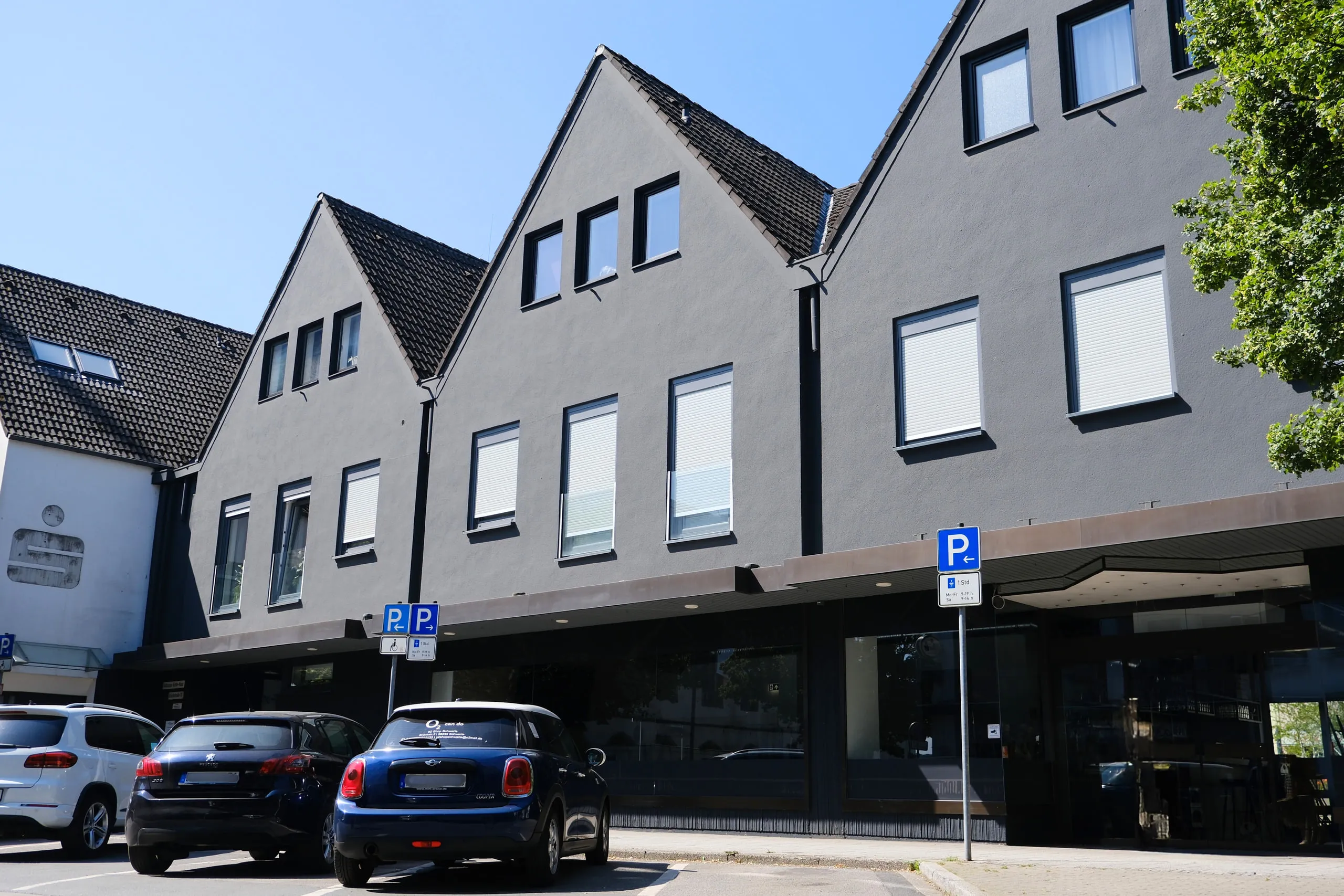 Wohn- und Geschäftshaus mit dunkler Fassade und drei Giebeln