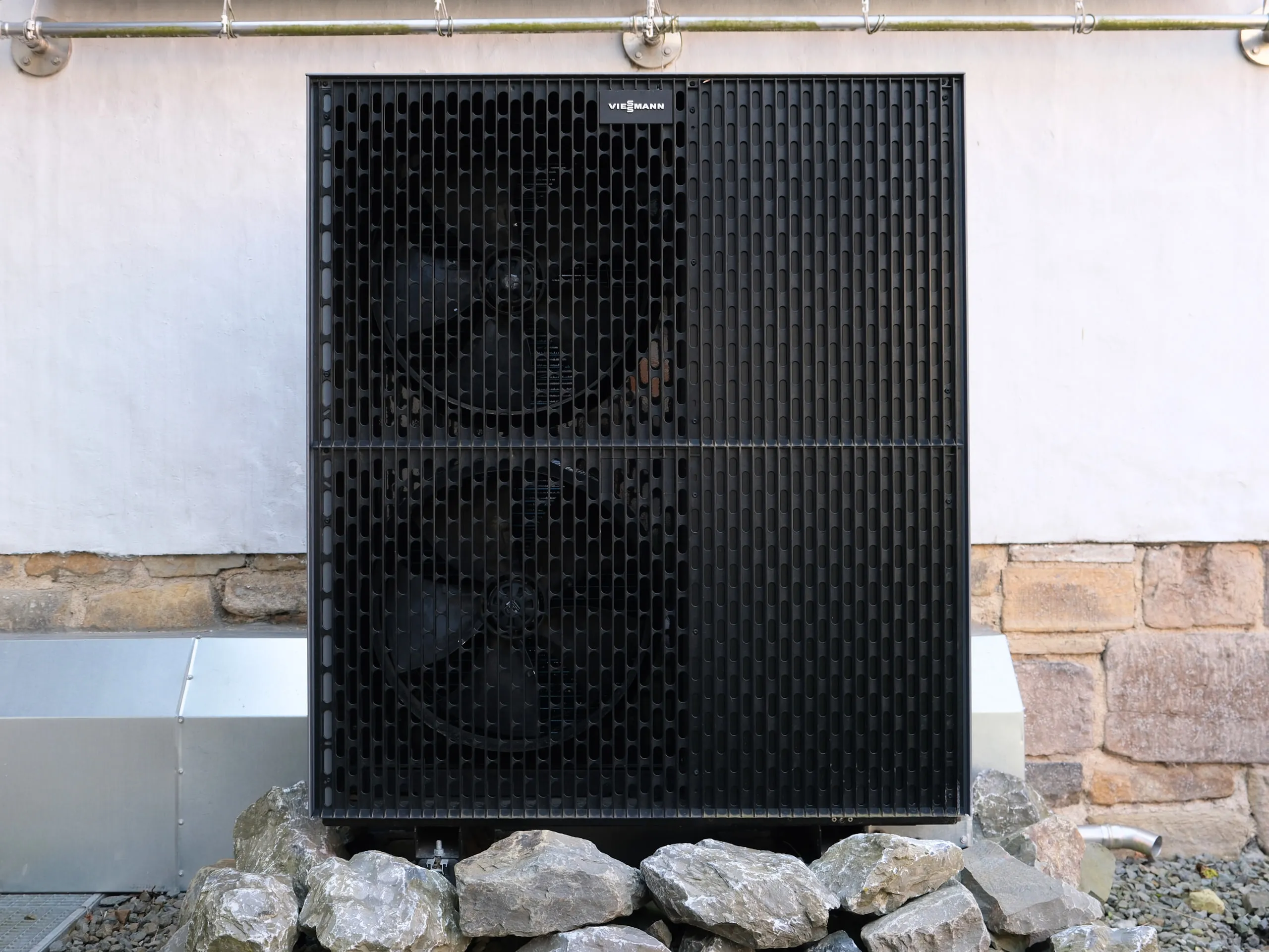 Außeneinheit einer Viessmann-Wärmepumpe auf einem Steinbett vor der Hauswand